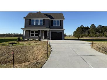 Two-story home with gray siding, a dark roof, and a paved driveway leading to an attached garage at 22 Wynd Crest Way, Benson, NC 27504