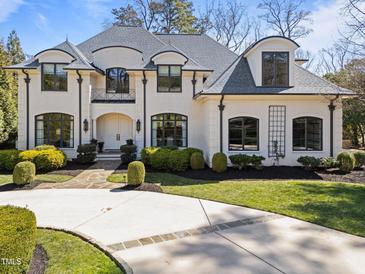 Stately white brick home featuring manicured landscaping and a circular driveway at 2710 Cambridge Rd, Raleigh, NC 27608