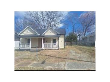 Charming bungalow featuring a cozy front porch, painted a warm neutral color under a blue sky at 614 Oak St, Burlington, NC 27215