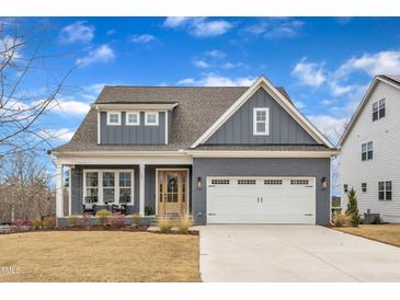 Charming two-story home with a two-car garage, a quaint front porch, and manicured landscaping at 112 Sire Ct, Holly Springs, NC 27540