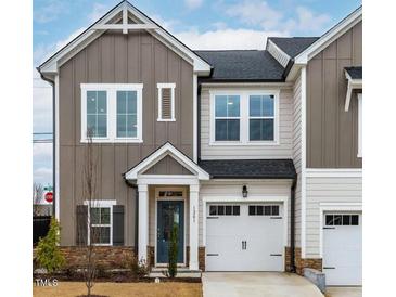 Charming two-story townhome with a well-manicured lawn, a blue front door and an attached garage at 1201 Canary Pepper Dr, Durham, NC 27713