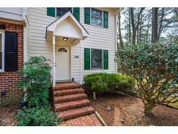 Charming two-story townhome with landscaped yard, brick walkway and white door with green shutters at 121 Westview Dr # 106, Carrboro, NC 27510