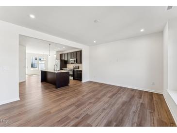 Spacious living room with modern hardwood flooring and an open layout leading to the kitchen at 1430 Cooper St, Sanford, NC 27330