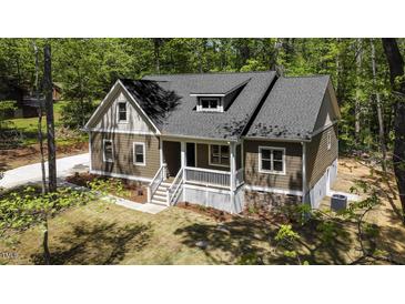 Inviting exterior view of home with covered porch, attractive siding, and beautifully landscaped yard surrounded by mature trees at 149 Amber Rd, Timberlake, NC 27583