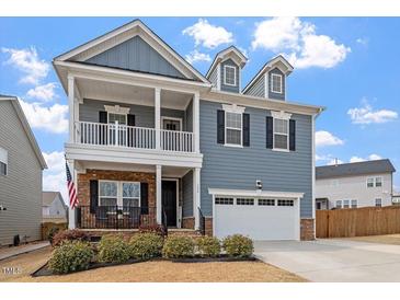 Charming two-story home features a welcoming front porch, a two-car garage, and classic blue siding at 204 Cassada Ct, Holly Springs, NC 27540