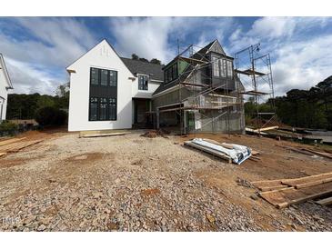 New construction home showing modern design elements and under-construction exterior finishes and professional scaffolding at 3405 Makers Circle, Raleigh, NC 27612