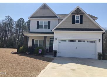 Two-story home with a two car garage, neutral siding and black shutters, landscaping, and a blue sky at 433 Falling Brook Dr, Kenly, NC 27542