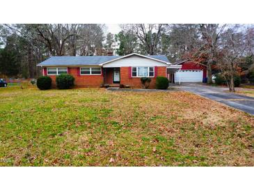 Charming brick home featuring a well-manicured front yard and a detached two car garage at 4709 Stafford Dr, Durham, NC 27705