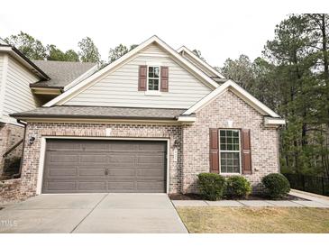 Charming brick home featuring a two-car garage, complemented by lush greenery and traditional shutters at 525 Rockcastle Dr, Cary, NC 27519