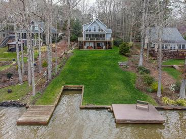 Lake house with a well-kept lawn that slopes down to the water and a dock at 651 Sagamore Dr, Louisburg, NC 27549