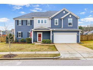 Charming two-story home featuring blue siding, a well-manicured lawn, and a two-car garage at 709 Teal Lake Dr, Holly Springs, NC 27540