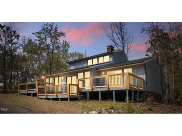 Exterior view showcasing a wooden deck with railing and gray siding and a view of the sunset in the background at 75 Traceway N, Sanford, NC 27332