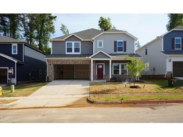 Two-story home features gray siding, brick accents, open garage and newly sodded yard at 157 Klamath Dr, Garner, NC 27529