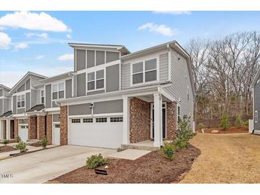 Charming gray townhome featuring a brick facade, two-car garage, and manicured landscaping at 193 Millennium Dr, Pittsboro, NC 27312