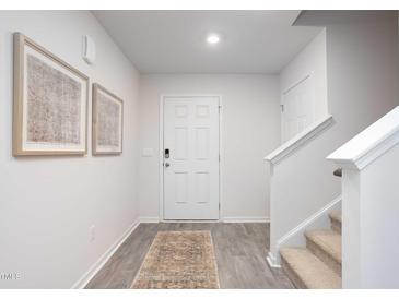 Bright foyer with gray wood flooring, white walls, staircase, and stylish decor at 2160 Monk Dr, Haw River, NC 27258