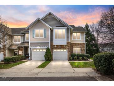 Charming townhome with a two-car garage and stone and siding exterior, set against a colorful sunset sky at 2302 Wispy Green Ln, Raleigh, NC 27614