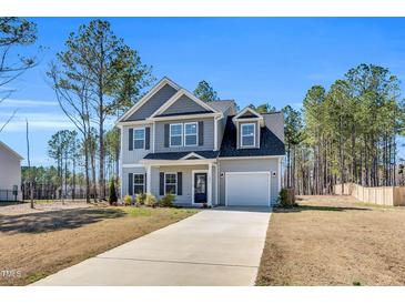 Charming two-story home features a long driveway, attached garage, and beautifully manicured lawn at 286 Beacon Hill Rd, Lillington, NC 27546