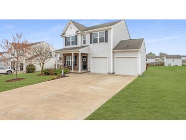 Charming two-story home with a well-manicured lawn, two-car garage, and inviting front porch at 509 Horseman Park Pl, Wendell, NC 27591