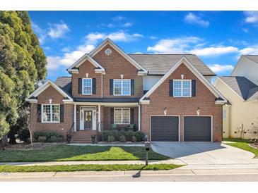 Charming brick home with manicured lawn, two-car garage, and inviting front porch at 12404 Beauvoir St, Raleigh, NC 27614