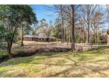 Charming brick home with mature trees and creek side appeal in lush green front yard at 1704 Cypress Dr, Henderson, NC 27536