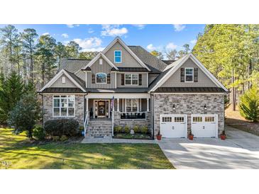 Charming two-story home featuring a stone facade, covered front porch, and an attached two-car garage at 260 Crestdale Dr, Clayton, NC 27520