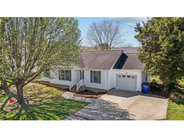 Charming single-story home with white siding, a garage, and a well-maintained front yard with mature trees at 309 Old Farm Dr, Graham, NC 27253