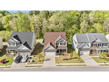 Charming two-story home featuring a well-manicured lawn and a two-car garage, surrounded by lush trees and blue skies at 69 Florence Dr, Clayton, NC 27527