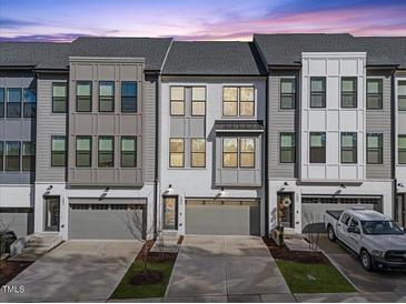 Charming townhome showcases a contemporary design with a two-car garage, and a gray and white color scheme at 1207 Corkery Ridge Ct, Cary, NC 27519