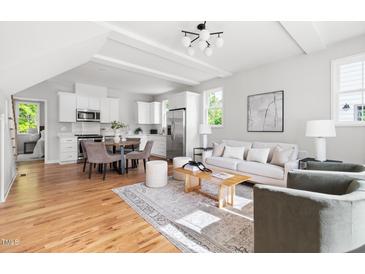 Bright, open living area featuring hardwood floors, modern decor, and seamless flow into the kitchen and dining spaces at 2816 Cascadilla St, Durham, NC 27704