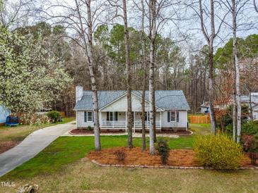 Charming single story home featuring a landscaped front yard and covered porch, complemented by mature trees at 5216 Passenger Pl, Raleigh, NC 27603