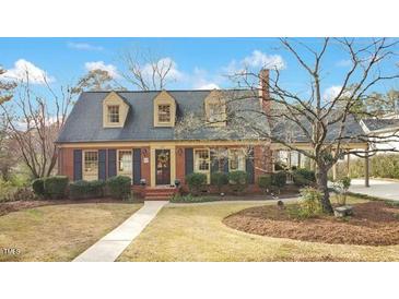 Charming brick home featuring dormer windows, manicured landscaping, and mature trees at 527 N Main St, Wake Forest, NC 27587