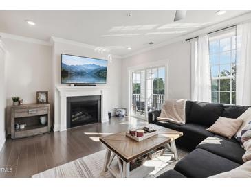 Bright living room featuring a fireplace, mounted television, and sliding door access to a small balcony at 10320 Sablewood Dr # 107, Raleigh, NC 27617