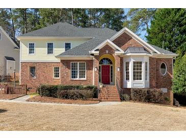 Charming brick-and-siding home featuring an arched doorway and well-manicured landscaping at 509 Edgemore Ave, Cary, NC 27519