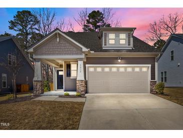 Charming home featuring a two-car garage, stone accents, and lovely landscaping at dusk at 5212 Huntley Overlook Dr, Durham, NC 27703