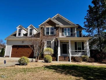 Charming two-story home featuring stone accents, a covered porch, and a well-manicured lawn at 61 Langdon Pointe Dr, Garner, NC 27529