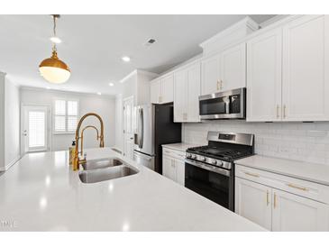 Bright kitchen features white cabinets, stainless steel appliances, subway tile backsplash and large island at 6434 Astor Elgin St, Raleigh, NC 27616