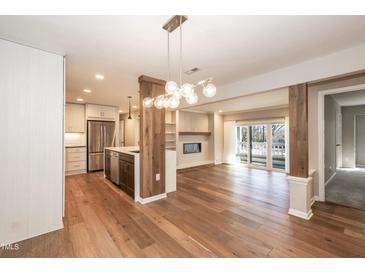 Open-concept living space with hardwood floors, modern lighting, fireplace, and kitchen view at 700 Bishops Park Dr # 205, Raleigh, NC 27605