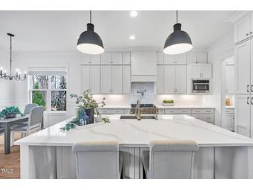 Bright kitchen boasts a large island with quartz countertops and stainless steel appliances at 8201 Southmoor Hill Trl, Wake Forest, NC 27587