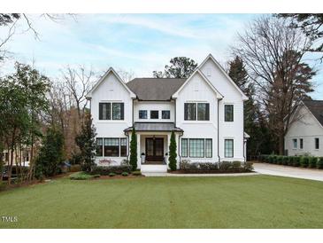 Elegant white two-story home featuring a manicured lawn and classic architectural details, offering timeless curb appeal at 909 Lake Boone Trl, Raleigh, NC 27607