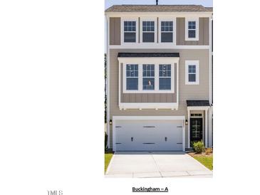 Charming townhouse featuring neutral siding, a two-car garage, and classic architectural details at 10004 Secluded Garden Drive Rd # 180, Apex, NC 27523