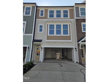Charming townhome featuring a spacious garage, light gray siding, and large windows for abundant natural light at 10004 Secluded Garden Drive Rd # 180, Apex, NC 27523