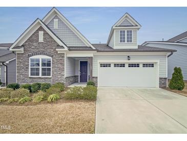 Charming home featuring stone accents, a two-car garage, and well-maintained landscaping at 157 Auburn Village Blvd, Raleigh, NC 27610