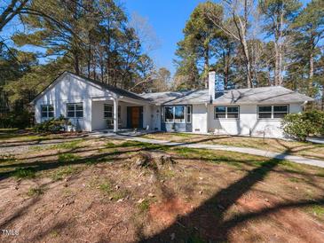 Charming single-story home with a white exterior, covered porch, and lush landscaping, nestled among tall trees at 205 Old Greensboro Rd, Chapel Hill, NC 27516