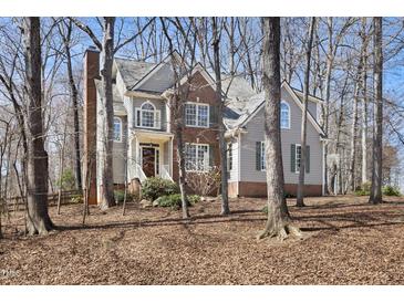 Charming two-story home with brick and siding exterior, surrounded by mature trees and landscaping at 2325 Old Oak Pl, Hillsborough, NC 27278