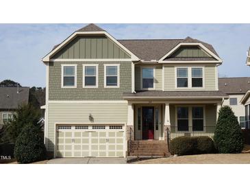 Charming two-story home featuring a mix of sage green siding, brick accents, and an inviting front porch at 309 Orange Blossom Ct, Wake Forest, NC 27587