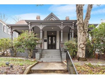 Charming historic home featuring a covered porch with detailed columns and inviting entryway, landscaping, and mature trees at 321 E Lane St, Raleigh, NC 27601