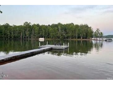 Lakefront view featuring a dock and seating area on the water with treeline in the background at 55 Waters Edge Loop, Henderson, NC 27537