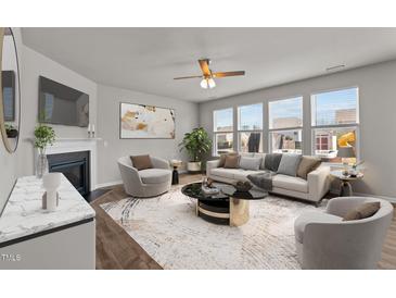 Bright living room with large windows, fireplace, ceiling fan, neutral tones and stylish décor at 717 Tailrace Falls Ct, Wake Forest, NC 27587