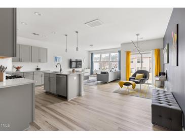 Bright, open-concept living room with sleek finishes and a modern kitchen featuring stainless steel appliances at 1019 Navigon Dr, Durham, NC 27713