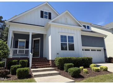 Charming home with white siding, covered porch, manicured landscaping, and attached two-car garage at 1564 Highpoint St, Wake Forest, NC 27587
